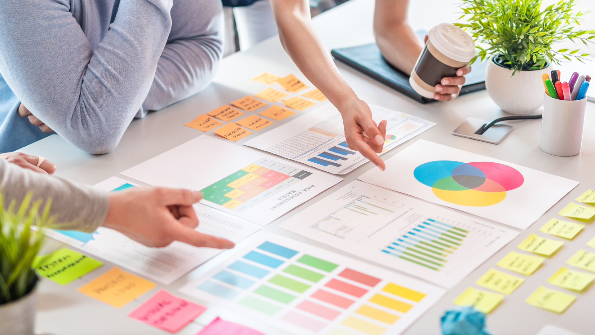 Eine Gruppe von Personen arbeitet gemeinsam an einem Projekt an einem Tisch, umgeben von Notizen und Dokumenten.