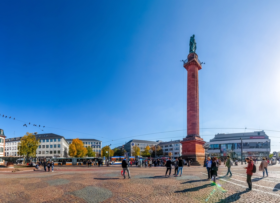 Großes Denkmal im Stadtzentrum von Darmstadt, umgeben von einem belebten Platz und modernen Gebäuden.